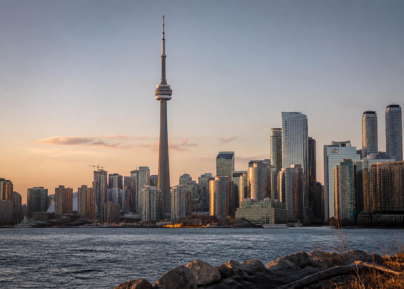The CN Tower rising above the Toronto skyline at golden hour, seen from the lakeshore